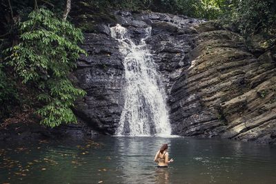 Waterfall amidst trees against rock formation