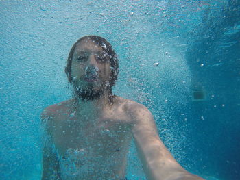 Underwater portrait of a boy in the bubbles in the outdoor pool in the summer