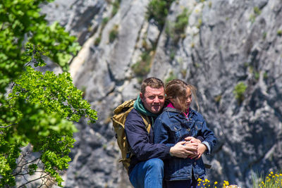 Portrait of man and girl standing against rock