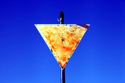 Low angle view of arrow sign against clear blue sky