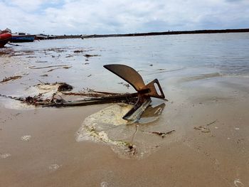 Rusty metal on beach against sky