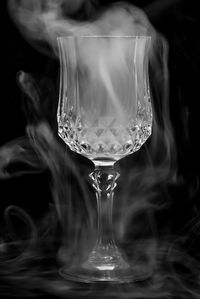 Close-up of wineglass with smoke against black background