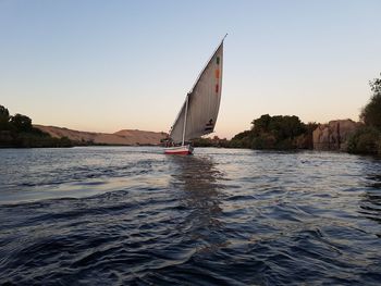 Sailboat sailing on sea against clear sky