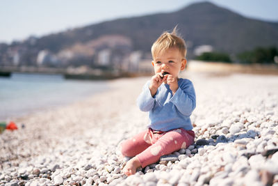 Boy sitting on pebbles