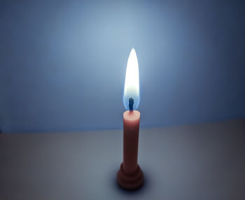 Close-up of illuminated candles on table against dark background