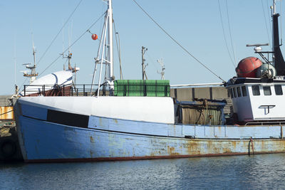 Boats moored at harbor against clear sky