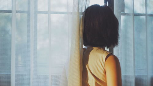 Rear view of woman looking through window