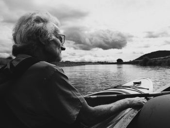 Close-up of senior man kayaking in lake against sky