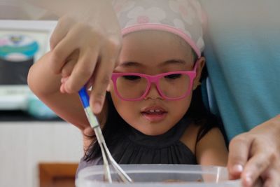 Close-up of hand helping girl preparing food on table