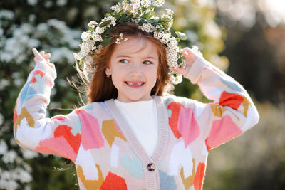 Happy smiling kid girl 6-7 year old wear knit colorful sweater wreath hairstyle with flowers