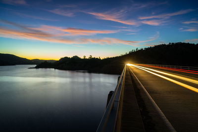 Light trails on road against sky at sunset