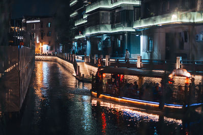 Canal amidst buildings in city at night