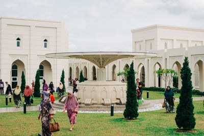 People in front of historic building against sky