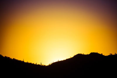 Scenic view of silhouette mountains against orange sky