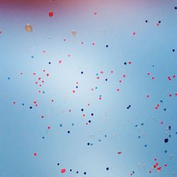 Low angle view of balloons against blue sky on sunny day