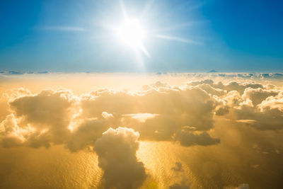 Airplane view of sky landscape with clouds, ocean with mountain peak and sunset shining sun