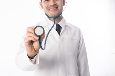 Midsection of doctor holding stethoscope over white background