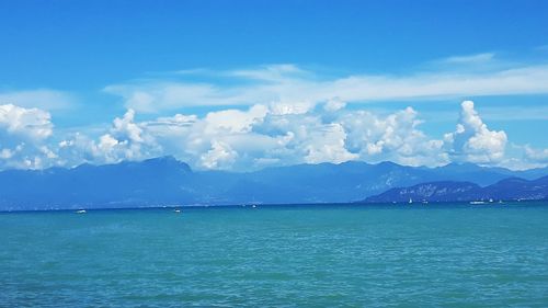 Scenic view of sea and mountains against blue sky