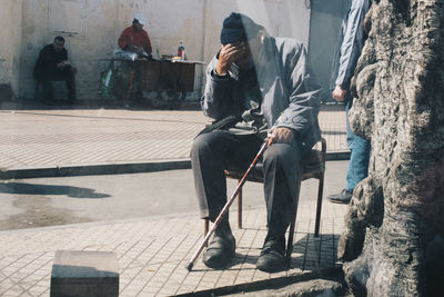Full length of man with head in hand sitting on street