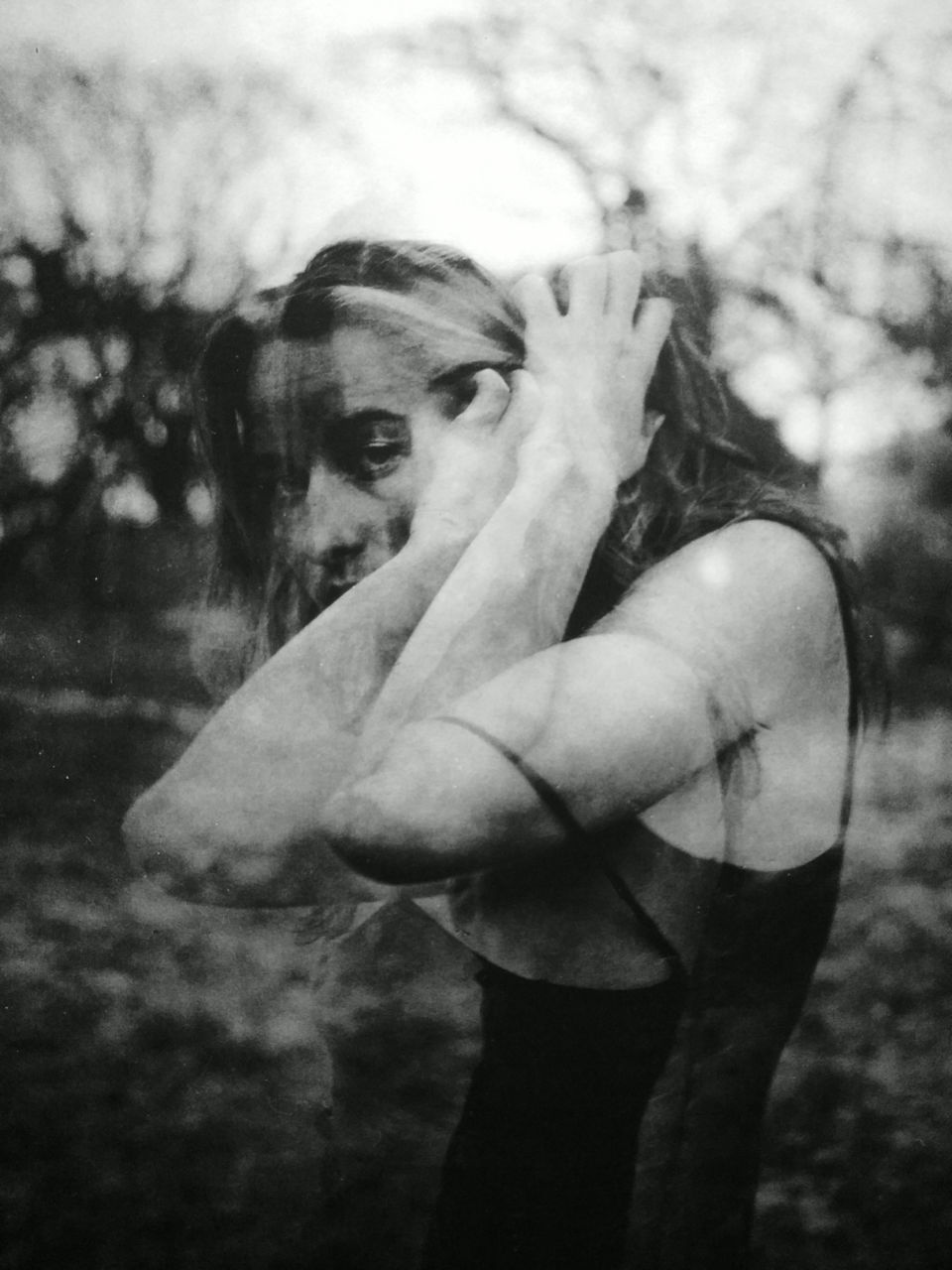 PORTRAIT OF WOMAN COVERING FACE WITH HAND ON HAIR