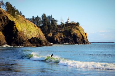 Scenic view of sea and surf against sky with lighthouse 