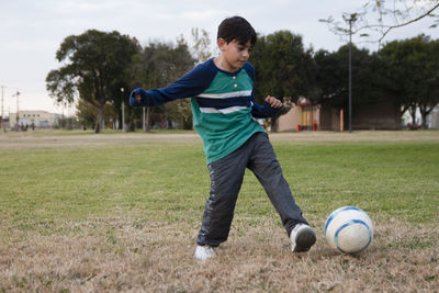 Full length of boy playing soccer at park