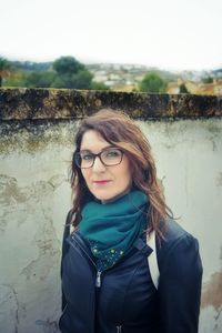 Portrait of smiling young woman standing against wall