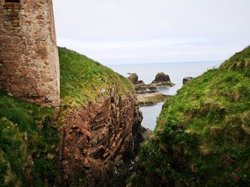 Scenic view of rocks by sea against sky