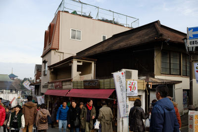 People at store in city against sky