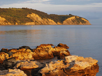 Scenic view of rocks by sea against sky