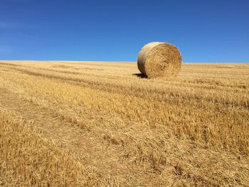 Hay bales on field against clear sky