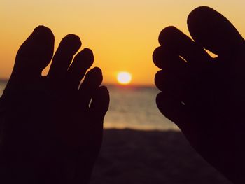 Close-up of silhouette hand against sky during sunset