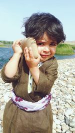 Portrait of boy holding stone while standing on pebbles