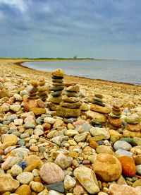 Stones on beach against sky