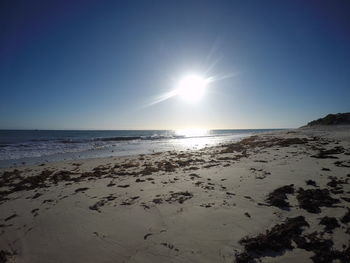 Scenic view of beach against clear sky at sunset