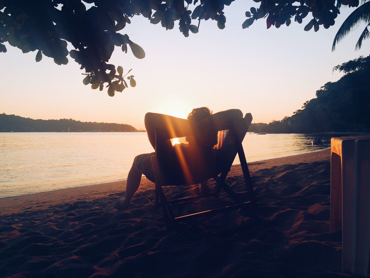 MAN RELAXING ON BEACH DURING SUNSET