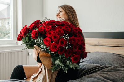 Charming young woman with a huge bouquet of red roses. flower delivery for holidays 
