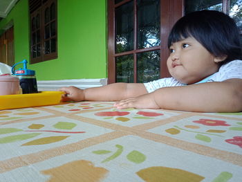 Portrait of cute girl lying on table at home