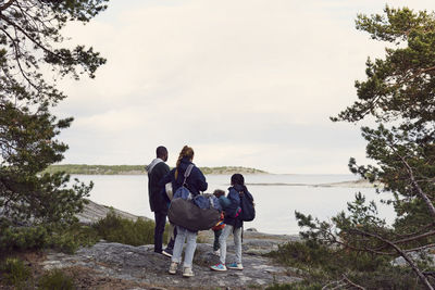 Rear view of family looking at lake against sky