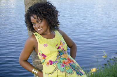 Portrait of young woman standing against lake