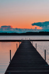 Pier over lake against sky during sunset