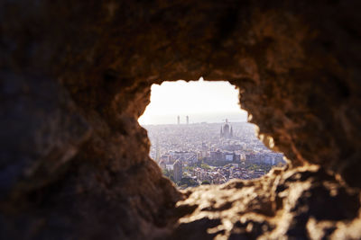 Cityscape seen through rocky hole during sunrise, bunkers del carmel, barcelona, spain