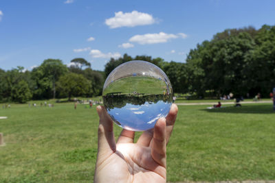 Midsection of person holding crystal ball on field