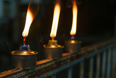 Close-up of lit candles in temple against building