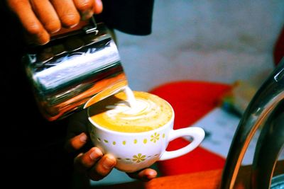 Cropped image of person pouring coffee in cup