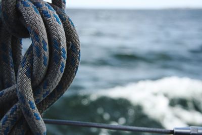 Close-up of rope tied to railing against sea