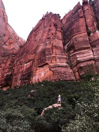 Man standing on rock formation against clear sky