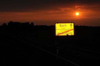 Information sign on railroad track against sky during sunset