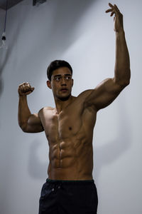 Shirtless muscular man standing against wall