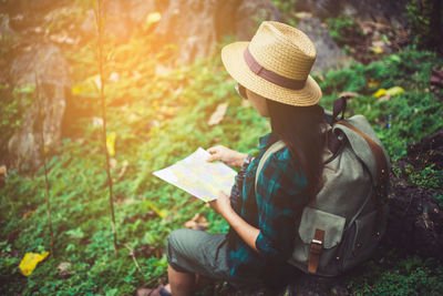Man holding book while sitting on land